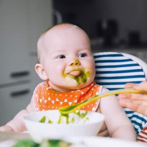 Baby with a messy face eating solids